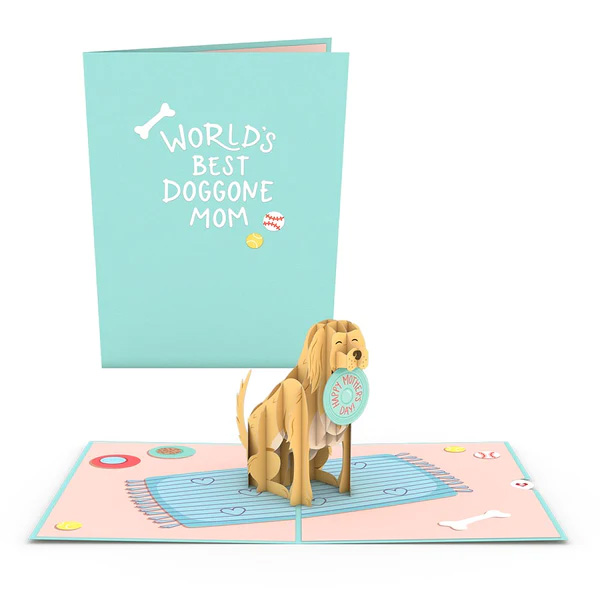 Pop up greeting card for mother's day for dog moms with dog holding a frisbee in its mouth while sitting on a beach towel with hearts on it.